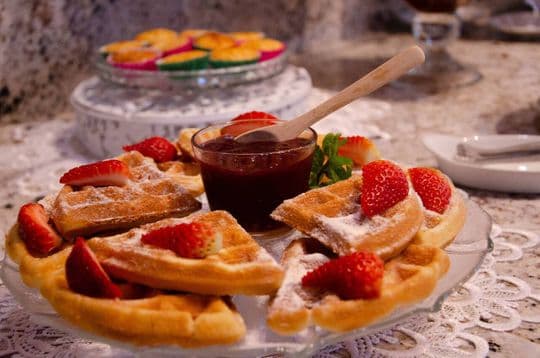 Waffles com morangos e calda de frutas vermelhas, em uma mesa do buffet